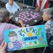 Stanovalci za mizo igrajo Štepkovo igro - spomin